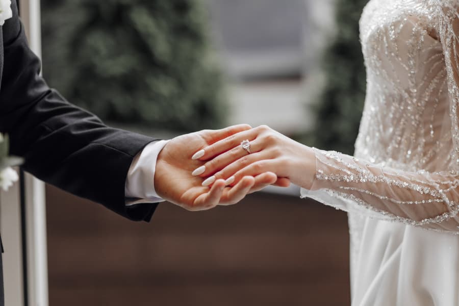 Groom holding brides hand with wedding ring